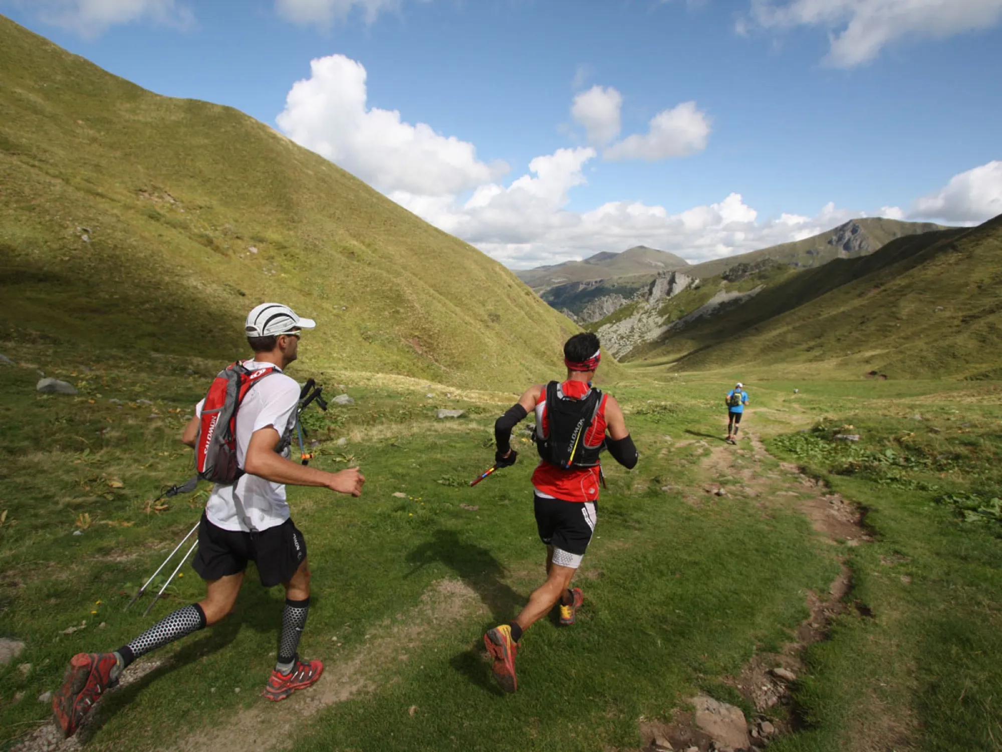 Deux traileurs en montée sur un sentier herbeux du massif du Sancy, sous les nuages