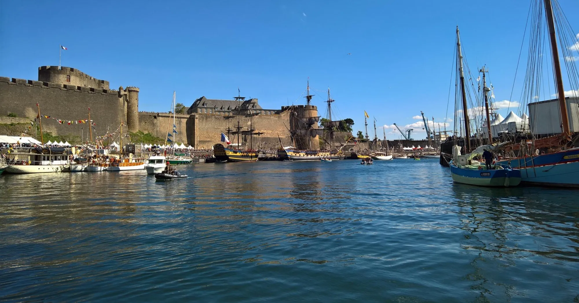 Le port de Brest et son château au bord de l'eau, voiliers à quai sous un ciel bleu