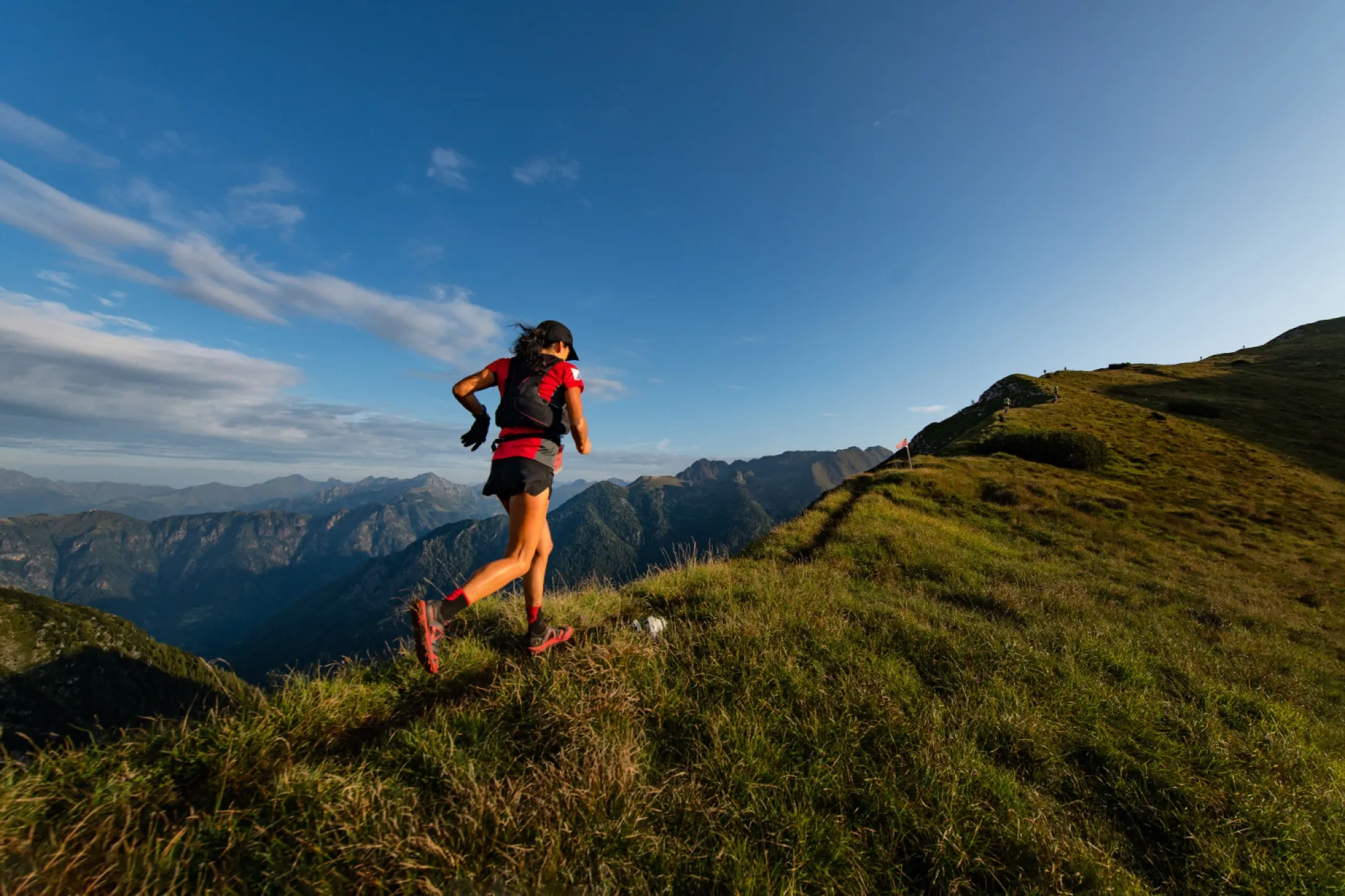 Traileuse en montée sur une crête herbeuse, chaîne de montagnes en arrière-plan