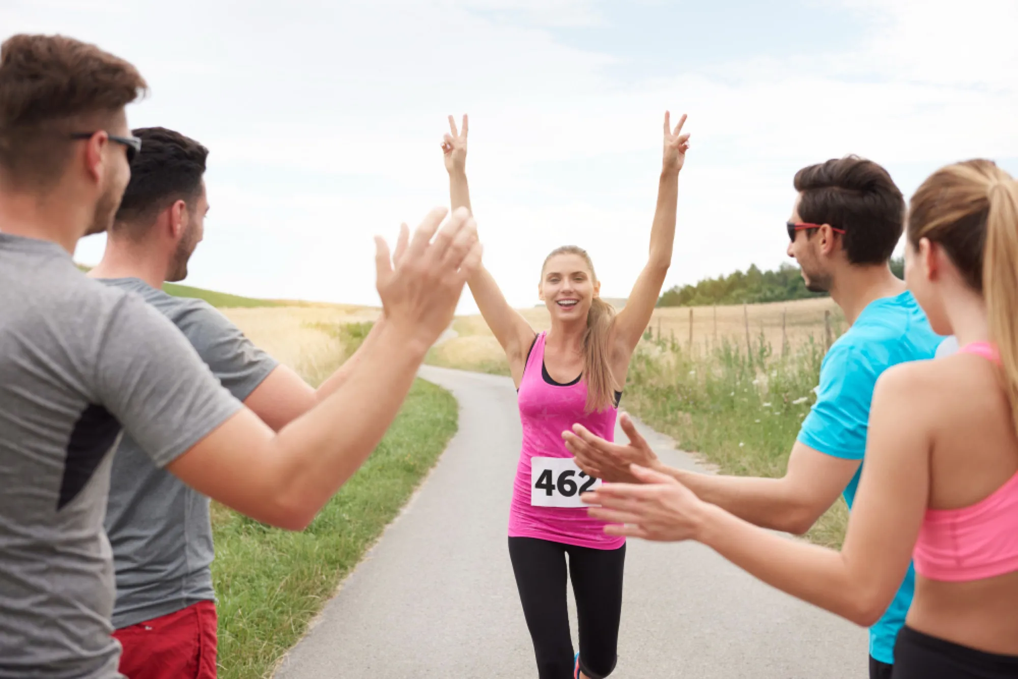 Coureuse franchissant une ligne d'arrivée les bras levés, félicitée par d'autres coureurs