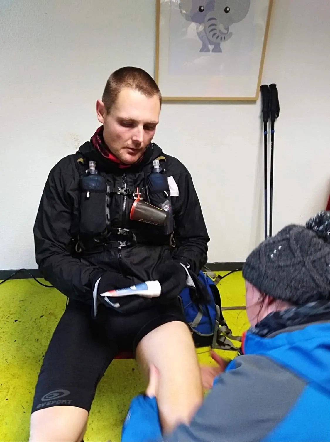 Julien Lainé assis au ravitaillement de La Renarde, gilet d'hydratation sur le dos, pendant qu'on lui masse la jambe